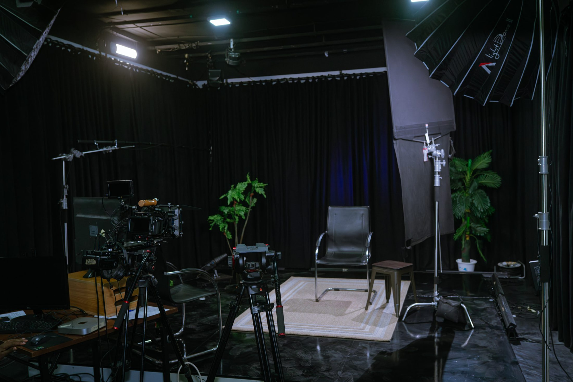 Film stage with cinema camera on tripod, softbox lighting and blackout drapes